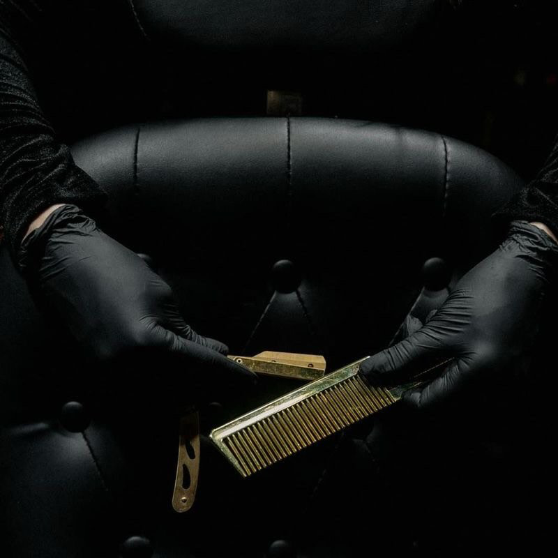 Barber holding a straight razor and brass comb at Eugene's Legacy Barbershop in Richmond, Virginia